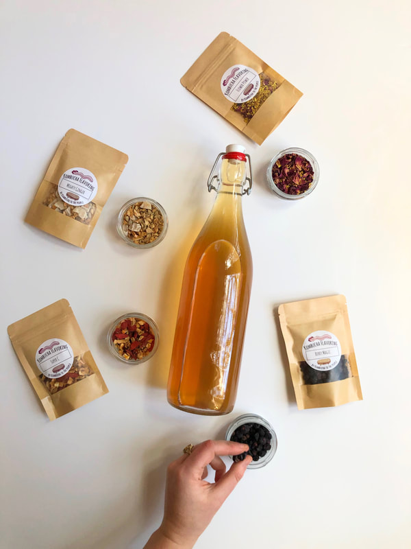 herbal kombucha flavorings for secondary fermentation with jar of kombucha surrounded by bags of flavorings